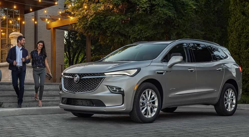 A silver 2024 Buick Enclave Avenir is shown parked near a Buick dealer.