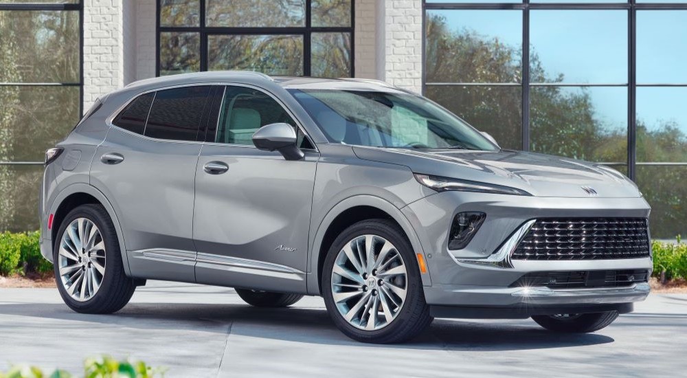 A silver 2024 Buick Envision Avenir parked outside a building.