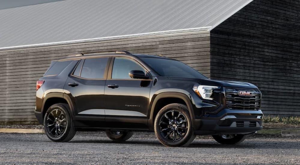 A black 2025 GMC Terrain parked near a barn.