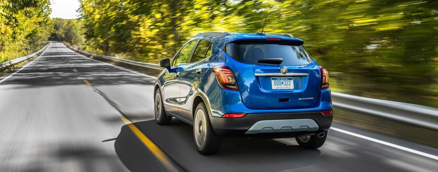Rear of a blue 2019 Buick Encore driving down a road.