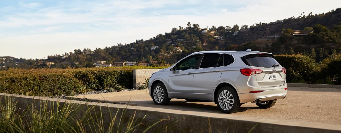 White 2019 Buick Envision parked on a pavement near a hedge.