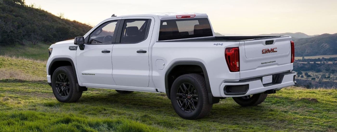 White 2024 GMC Sierra 1500 from the side parked in a grassy field.