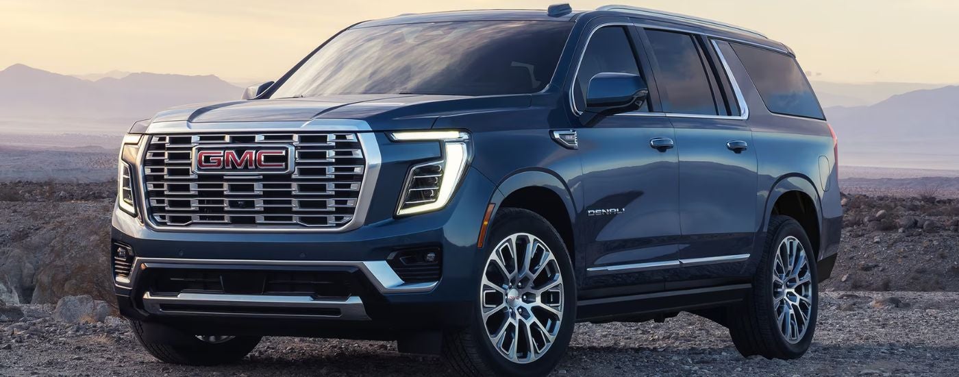 A blue 2027 GMC Yukon XL Denali parked off road.