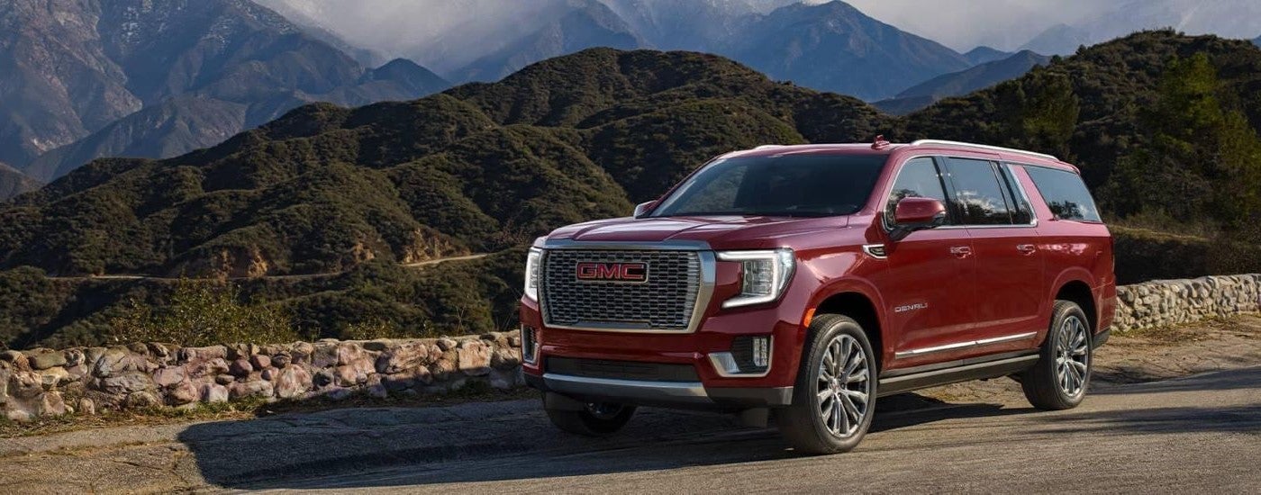 A red 2021 GMC Yukon XL Denali parked by mountains.