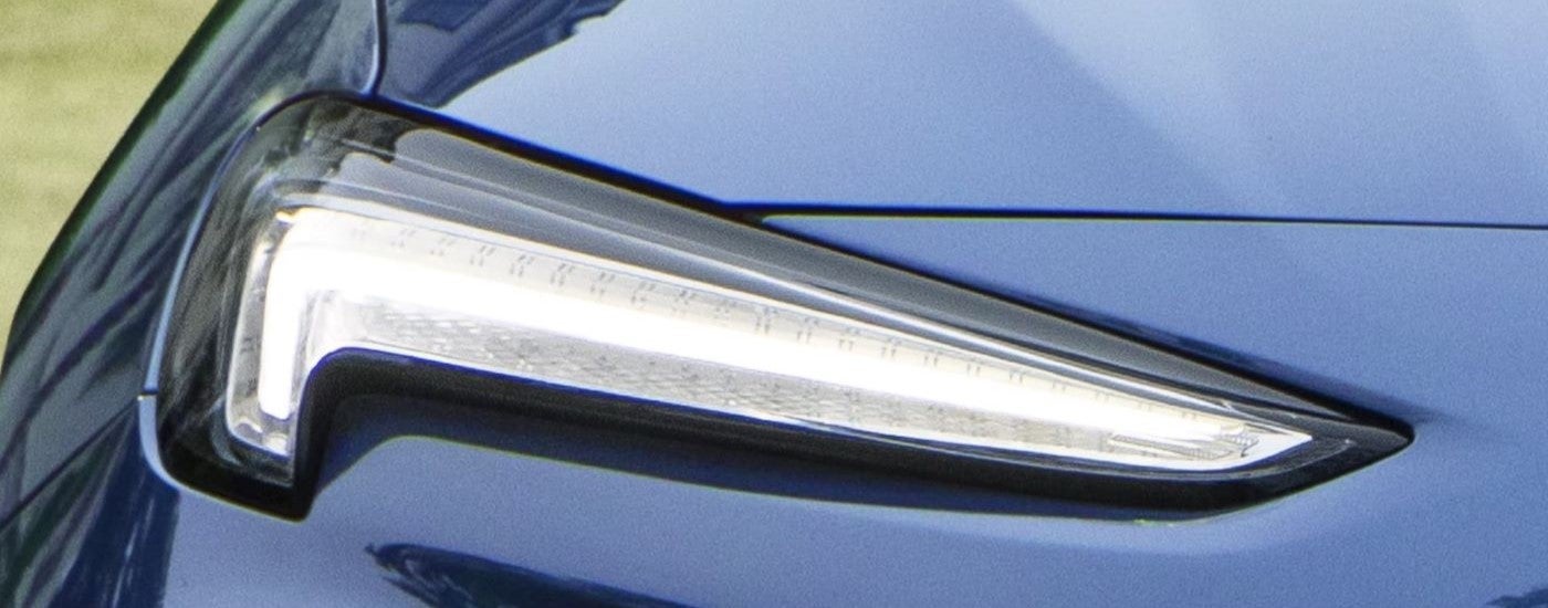 A close up shows the passenger side headlight on a blue 2024 Buick Encore GX Avenir.