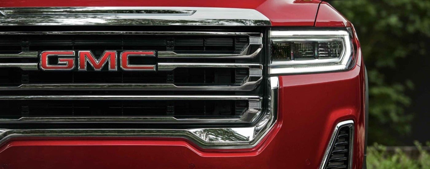 Close-up on the grille of a red 2023 GMC Acadia SLT.
