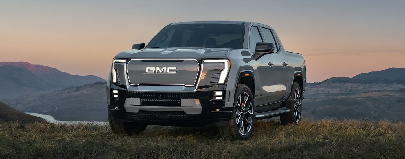 Grey 2025 GMC Sierra EV Denali parked on grass.