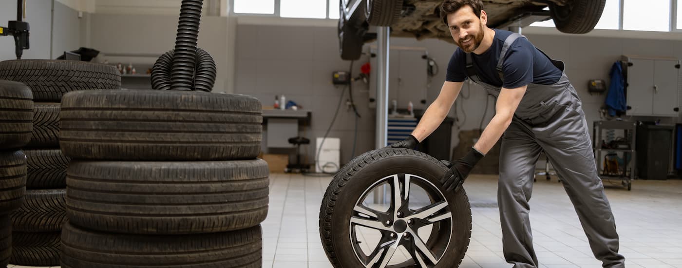 Mechanic rolling a tire in a garage.