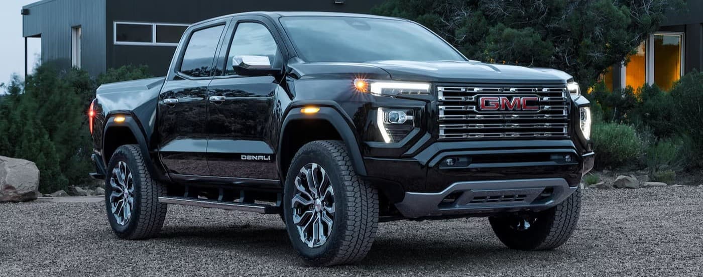 A black 2026 GMC Canyon Denali parked on gravel.