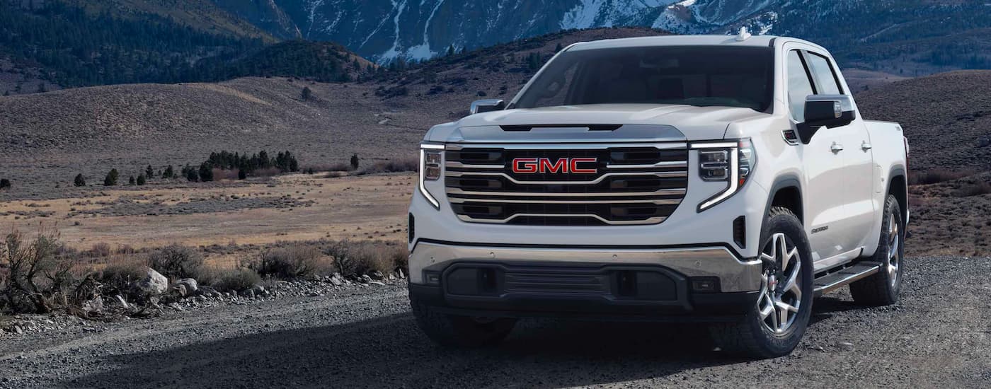 A white 2023 GMC Sierra 1500 parked on a dirt road and angled left.
