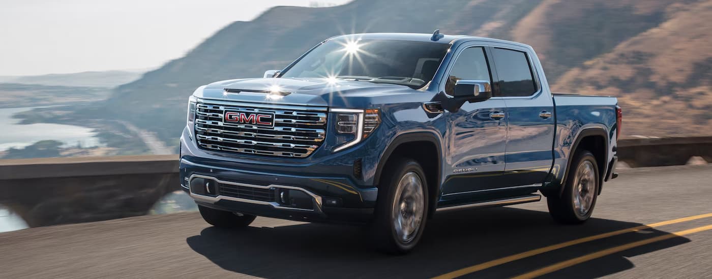 A blue 2025 GMC Sierra 1500 Denali driving on a highway